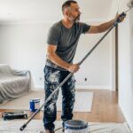 A man using a roller to demonstrate how to paint a room with smooth, even coverage.